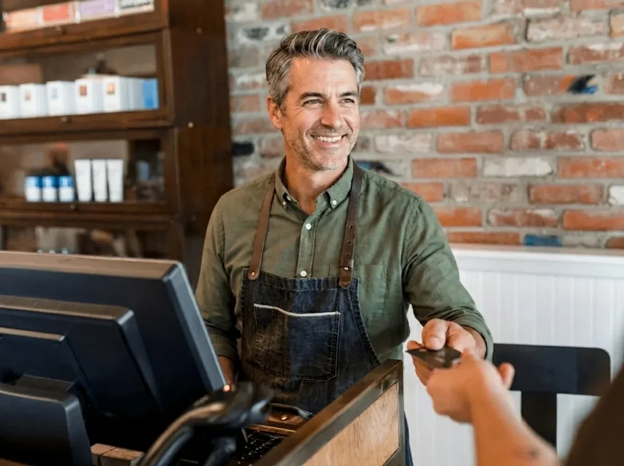 Smiling small business owner accepting a card payment at the register